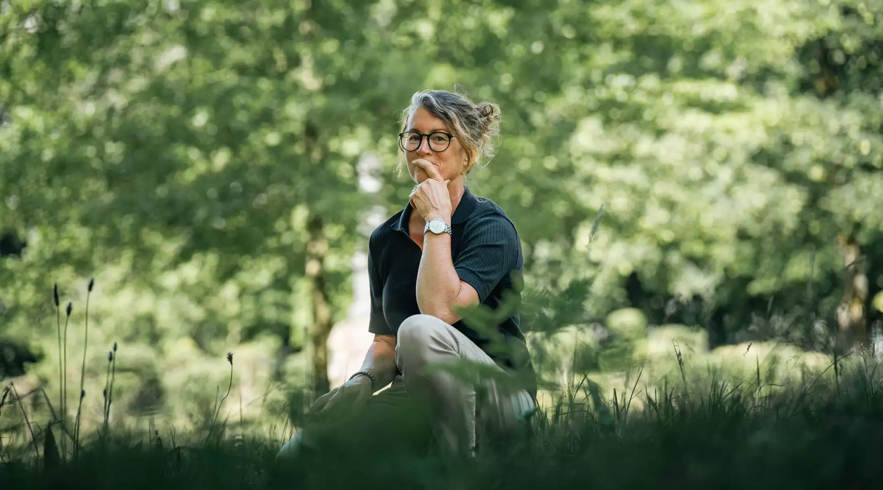 Fotografin Ines Preißer kniet nachdenklich im sommerlichen Grün auf Pellworm