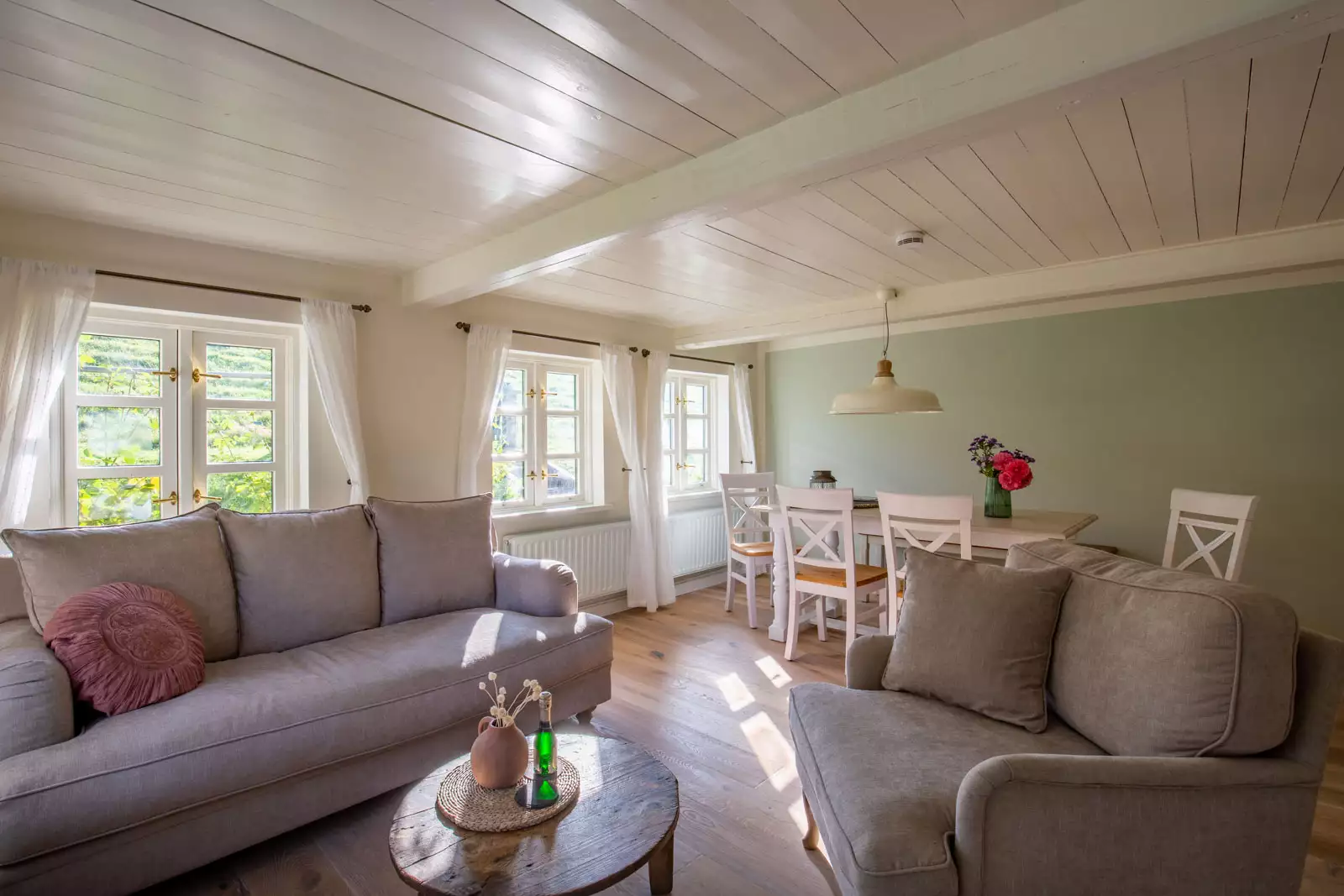 Offener Wohn- und Essbereich mit Holzbalkendecke und Sprossenfenstern in einem Ferienhaus auf Pellworm